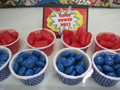 red, white and blue candies are in plastic cups on a table next to a candy bar