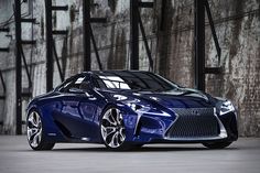 a blue sports car parked in front of a brick wall with graffiti on it's walls