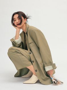 a woman is sitting on the ground with her legs crossed, wearing a coat and white socks