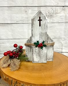 a white wooden church with holly and red berries on it sitting on top of a tree stump