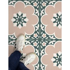 someone is standing on the floor with their feet propped up in front of a floral tile pattern