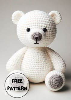 a crocheted white teddy bear sitting next to a button with the word free pattern on it