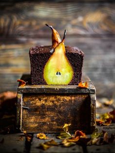 a piece of chocolate cake with a pear on top, sitting in a wooden box