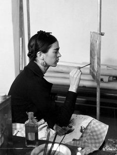 a woman sitting in front of an easel painting