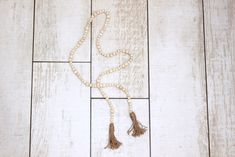 a white beaded necklace with tassels on a wooden floor