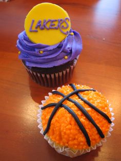 two cupcakes with purple frosting and yellow icing, one decorated like a basketball