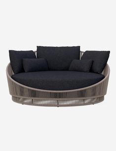 a round couch with black cushions and pillows