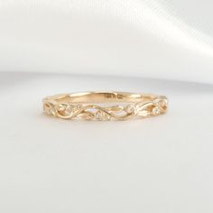 a yellow gold wedding band with three diamonds on the top and bottom, sitting on a white cloth