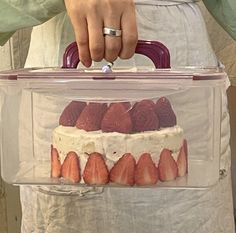 a person is holding a plastic container with strawberries in it and the lid has a cake inside