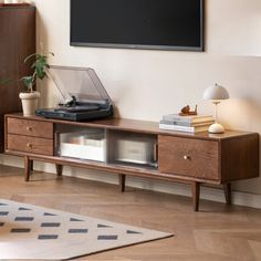 a record player is sitting on top of a wooden entertainment center in front of a flat screen tv