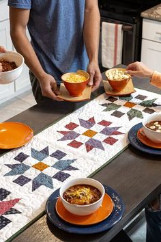 three people standing around a table with bowls of food