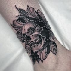 a black and white skull with flowers on it's head is seen in this tattoo design