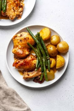 two plates with chicken, potatoes and green beans