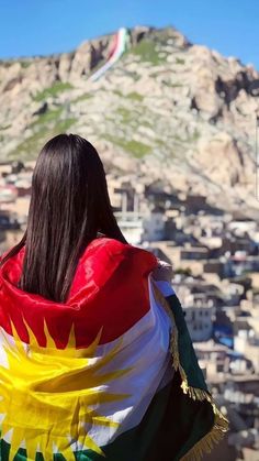 a woman with long hair wearing a flag scarf looking at the city below her head