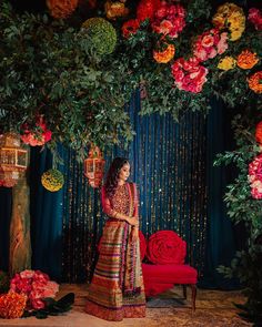 a woman in a red and gold outfit standing under a tree with flowers on it