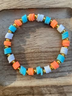 an orange, white and blue beaded bracelet sitting on top of a wooden table