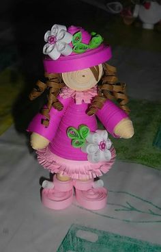 a small doll is wearing a pink dress and hat