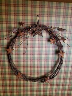 a wreath made out of branches with stars hanging from the front and sides on a checkered wall