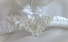 the bridal garter is adorned with swaroes and pearls, along with a satin bow