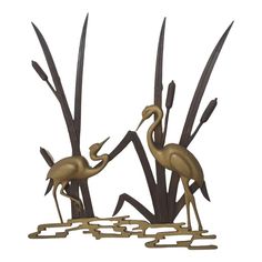 two metal birds standing next to each other on top of grass and plants with long, thin stems