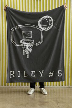 a person holding up a black banner with a basketball hoop on it and the words riley 5 written in white