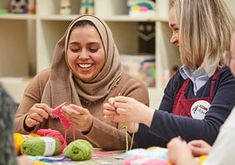 three women sitting at a table with yarn and crochet