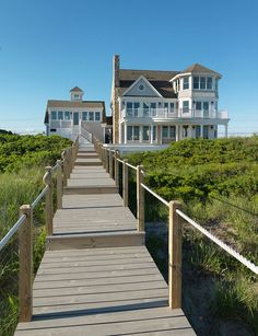 a wooden walkway leading to a large white house