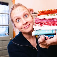 a woman is holding up some folded fabric