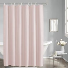 a white bath tub sitting next to a pink shower curtain