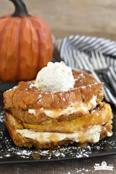 a stack of food sitting on top of a black plate next to a small pumpkin