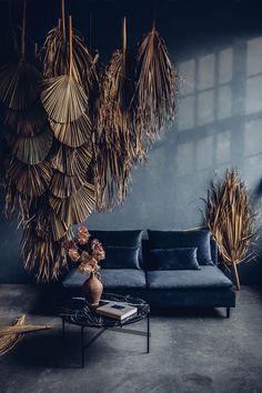 a living room with blue couches and palm leaves hanging from the wall above it