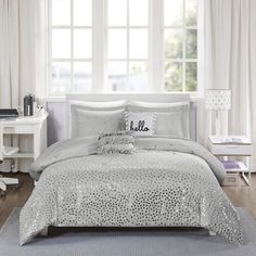 a bed with pink comforter and pillows in front of a white window sill