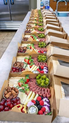 a long table filled with lots of different types of food in boxes on top of a counter