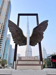 an angel statue in front of the burj building with skyscrapers in the background