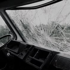 the interior of a car with shattered glass on it's windshield and trees in the background