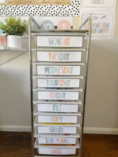 a metal rack with lots of cards on it in front of a white wall and wooden floor