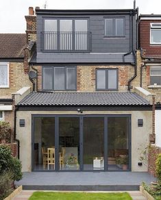 a house with an open patio and lawn area in front of it, surrounded by brick buildings