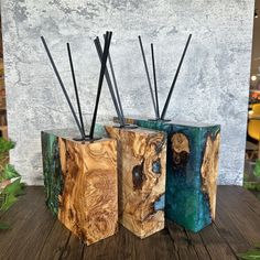 three wooden boxes with sticks sticking out of them on top of a wood table in front of a wall