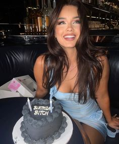 a woman sitting in front of a birthday cake