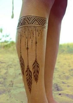 a woman's legs with tattoos and feathers on the side of her leg,