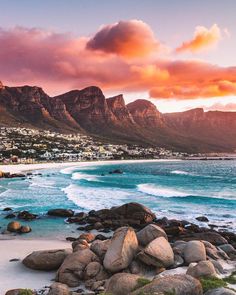 the beach is full of rocks and water with some mountains in the backgroud