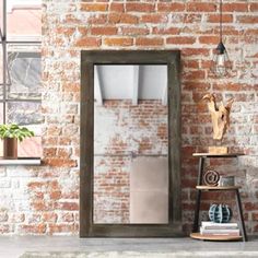 an old brick wall with a mirror and shelf on the floor in front of it