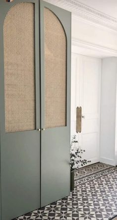 an open door in a room with black and white floor tiles on the floor, and a plant next to it