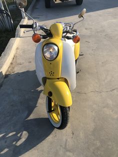 a yellow and white scooter parked on the street