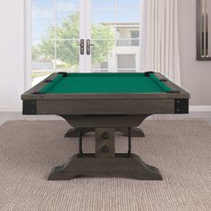 a pool table sitting on top of a carpeted floor next to a window with white curtains