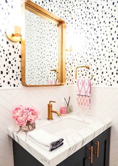 a bathroom with black and white wallpaper, gold fixtures and a mirror above the sink