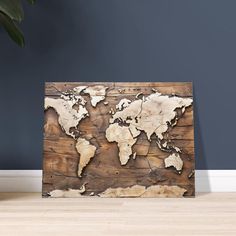 a wooden world map on the wall next to a potted plant