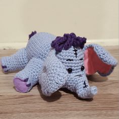 a crocheted elephant laying on the floor with it's head turned to the side