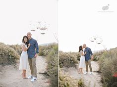 a man and woman standing on top of a dirt road next to bushes with balloons in the air