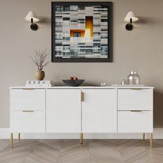 a white sideboard with two vases sitting on top of it next to a wall